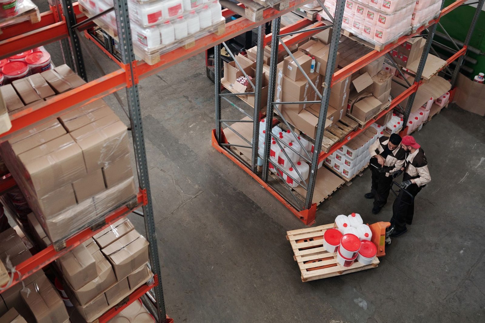 Operarios ordenando mercadería en estanterías de un depósito, vistos desde arriba